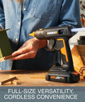 Person using Cordless Full Size Hot Glue Gun With 20V Power Share Battery And Charger, crafting a wooden model.