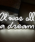 "It was all a dream" neon sign, warm white light, illuminated against a dark background.