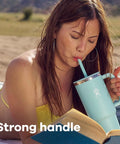 On The Fly 40 Oz Stainless Steel Travel Tumbler With Comfort Grip Handle And Leak Proof Straw Lid in use, strong handle, woman reading outdoors.