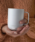 Keep Your Morning Brew Piping Hot With This App Controlled Smart Mug 10 Ounce White Heated Coffee Cup held in hands.