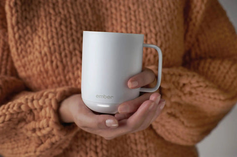 Keep Your Morning Brew Piping Hot With This App Controlled Smart Mug 10 Ounce White Heated Coffee Cup held in hands.