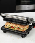 Alpha Living Electric Griddle Panini Press With Non Stick Coating, Stainless Steel 3 In 1 Sandwich Maker grilling a sandwich.