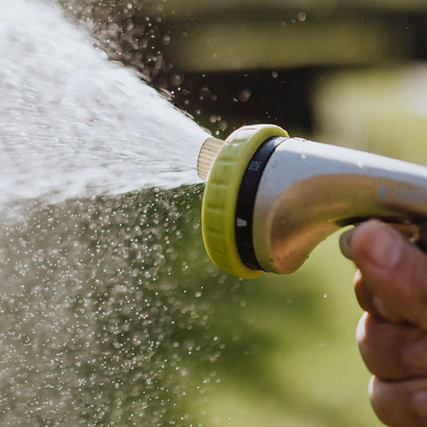 Close-up of hand holding trigger spray nozzle releasing mist, demonstrating Outdoor Misting Nozzles Set, Stainless Steel High-Pressure Fogger Heads