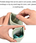 Close-up of a green purse with metal internal flex frame set, showing keys and measuring tape inside, DIY use.