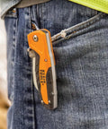 Electricians Utility Knife With Hawkbill Blade For Cable Skinning clipped onto jeans pocket, ergonomic rubber-grip handle visible