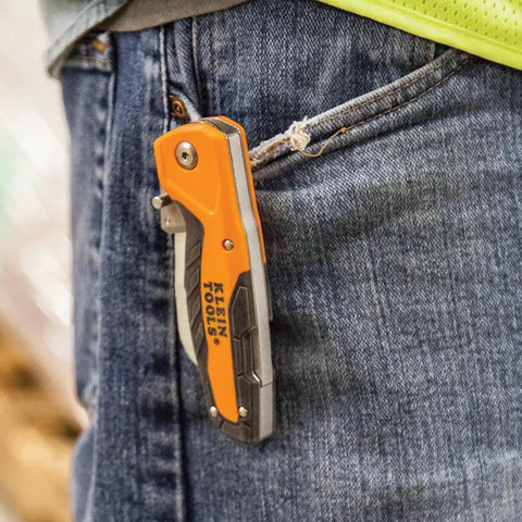 Electricians Utility Knife With Hawkbill Blade For Cable Skinning clipped onto jeans pocket, ergonomic rubber-grip handle visible