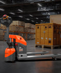 Aequanta Full Electric Pallet Jack positioned in a warehouse, showcasing its ergonomic handle and compact design for tight spaces.