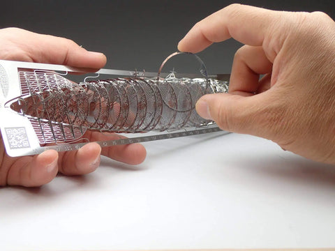 Hands assembling Hindenburg LZ129 1 to 1000 Scale Photo Etched Stainless Steel Model Kit, showcasing intricate etched components.