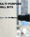 GMTOOLS 10-piece masonry drill bit set (1/8–1/2 in) with carbide tips mounted in a cordless drill against concrete.