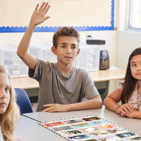 Student in classroom interacts with the Five Poster Basic Spanish Vocabulary Set With Photos for Classrooms displayed on table.