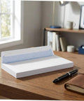 White Pro-Grade Self-Sealing Security Mailing Envelopes 115mm X 225mm displayed on a wooden desk with a pen and leather notebook
