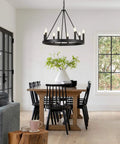 Eight-Light Wagon Wheel Chandelier in Black hanging over a dining table, showcasing farmhouse meets modern industrial style.