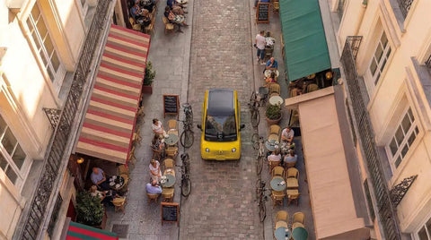 Premium Two Seater Electric Golf Cart Boasting A Killer 112 Mile Lithium Range Lightning Fast Four Hour Charging And High End Smart Cabin Features For Total Neighborhood Comfort driving through a quaint Parisian street.