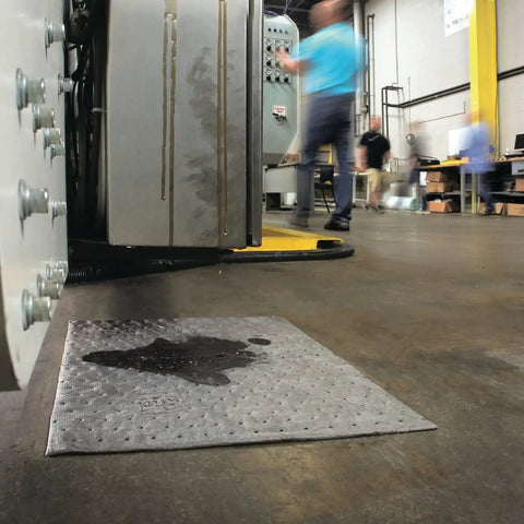 Premium Oil Absorbent Mat Pads 15 x 20 Inches placed on workshop floor absorbing spill near machinery