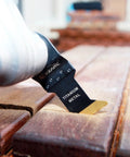 EZARC titanium oscillating tool blade cutting wood plank; black blade labeled TITANIUM METAL, side view