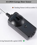 Close-up of black 41A5034 sending sensor with amber LED for Garage Safety Sensor Kit For 1997 To Current Garage Door Openers With Safety Sensors Includes Two Sensors For Receiving And Sending Replacement G801CBP Compatible With LiftMaster Sears Chamberlain Craftsman Openers No Hassle Install Plug And Play