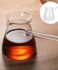 Glass coffee pot with side handle on wooden table, filled with coffee. Inset image of empty pot.