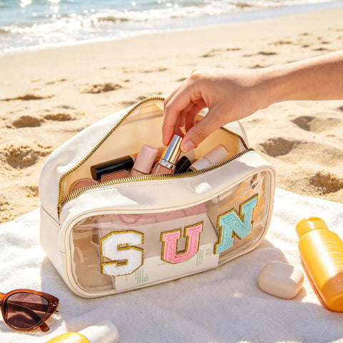 Clear Sunscreen Zipper Bag For Beach And Pool, Waterproof See Through Makeup Pouch With Glitter Sun Design on sand with contents