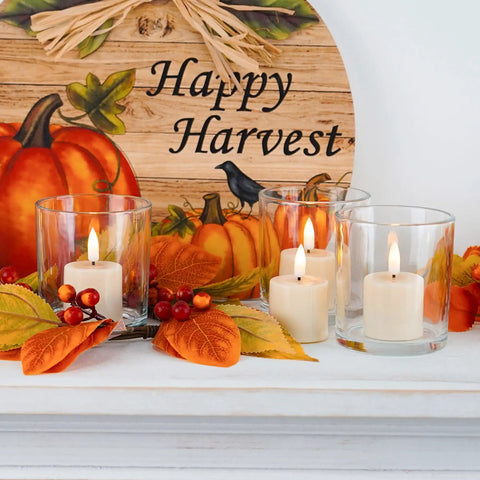 Flameless votive candles in glass holders on a mantle with fall decor and Happy Harvest sign
