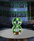 8.5 Inch Pixel Game Light Up Number 8 on table with pixel pattern, Happy Birthday sign, retro arcade style party atmosphere