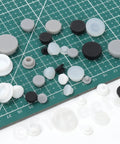 Massive Set Of 120 White Rubber Plugs In 9 Sizes For Round Holes, Heavy Duty Silicone Snap Locking Stopper Kit Perfect For Furniture Repair And DIY Projects Around The House., assorted white and black silicone hole plugs in multiple sizes on cutting mat