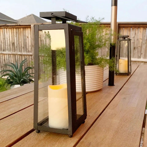Outdoor Solar Lanterns With Flameless Candles Two Pack 11 Inch Tall Black Metal Glass Lanterns For Patio on a wooden table