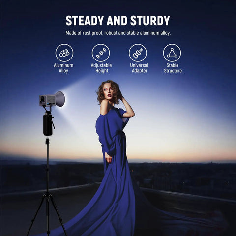 Model with versatile aluminum photography light stand 1.5 to 6.4 feet telescoping tripod and strobe against a dusky backdrop.