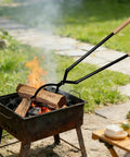 Using 42 Inch Detachable Fire Tongs And Poker Set With Carrying Bag to adjust logs in outdoor bonfire, shown in use.