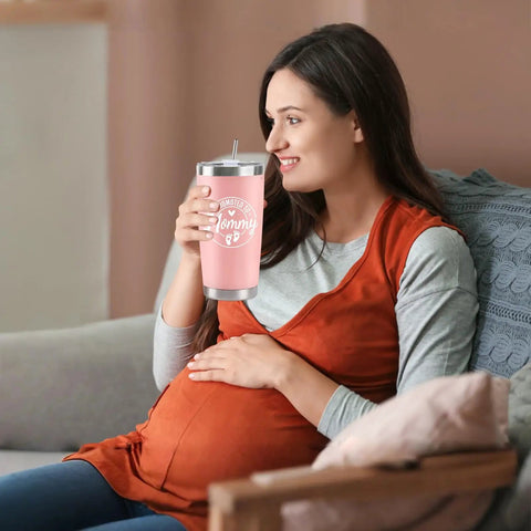 Celebrate The Freshly Minted Arrival Of New Mama And Papa With This Awesome Gift Set For Couples Featuring Matching Tumblers Paired With A Warm Cozy Candle Perfect For Baby Showers First Fathers Day And Parenting Squad Celebrations. Pregnant woman smiling while holding a pink insulated tumbler.