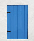 Blue wooden door with black Beefy Heavy Duty Extended Door Hinge With Ball Bearing For Wooden Gates And Barn Doors Black Industrial Strap Hinges Slotted Design For Easy Installation And Enhanced Stability visible against a white wall.