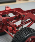 Close-up of 12-Scale RC Aluminum Alloy Chassis Kit with metal gearbox, axles, and wheels showing red frame and suspension.