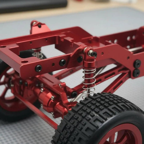 Close-up of 12-Scale RC Aluminum Alloy Chassis Kit with metal gearbox, axles, and wheels showing red frame and suspension.