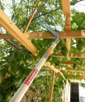 Long-handled tool reaching through trellis with fruit, showcasing Heavy Duty Pick Mattock For Tough Soil With Extra Thick Forged Steel, Ergonomic Hand Tool For Easy Cultivating And Weeding, 22.85 Inch Overall Length, 2.25 Inch Blade, Ideal Digging Tool For Gardens And Landscapes.