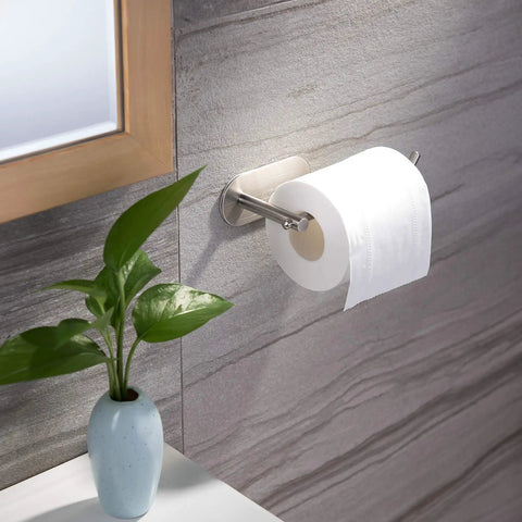 Self Adhesive Toilet Paper Holder For Bathroom And Kitchen Wall Mount Brushed Stainless Steel No Drill Easy Clean Stick On Design With Upward Bend Keeps Roll Secure And Accessible in bathroom scene with plant.