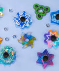 Colorful DIY fidget spinners with Fidget Spinner Bearings With Caps 24 Pack Chrome Steel Craft Set arranged on a blue surface.