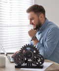 Novabright Vintage Copper Steampunk Gear Train Figurine For Desk Decor on office desk next to man using laptop