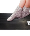 Feet in socks on Electric Foot Warmer Mat Portable Heated Rubber Floor Pad For Home Office Garage And Car 120 Watt Personal Space Heater Heats Quickly To 150 F Large 23 By 14 Inch Keeps Your Feet Toasty