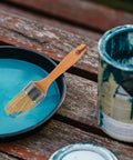 Wood handle paint stain brush with oval synthetic bristles resting on blue paint tray, part of 2 Piece Wood Handle Paint Stain Brushes With Oval Synthetic Bristles For Wood Stain And Wall Paint Deck Brush For Furniture And Wall Treatments This Pro Painting Tools Set Delivers Smooth Finishes And Easy Cleanup