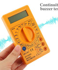 Hand holding 830D Digital Multimeter Tester with Buzzer 1999 Counts for AC DC voltage current resistance continuity diodes use.