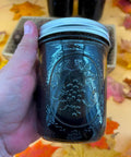 Black Walnut Wood Stain 1 Pint Water Based Non Toxic Low Odor Rich Dark Tone in a glass jar held against autumn leaves.