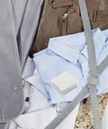 Eighty Piece Pack Of Invisible Adhesive Shirt Collar Stays with shirts and a carrying case in a styled arrangement.