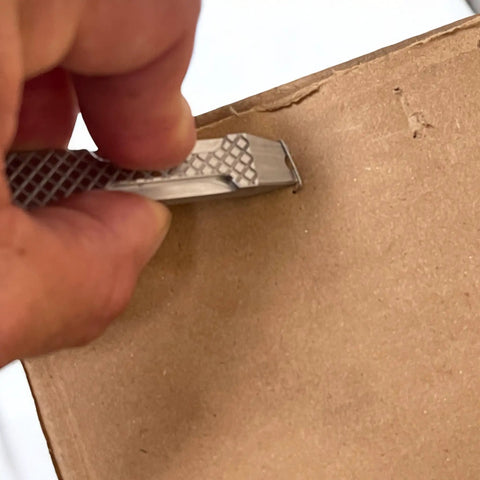 Person using Everyday Carry Mini Pry Bar Keychain With Screwdriver And Box Opener Heavy Duty Stainless Steel EDC Tool Pocket Pry Bar on cardboard