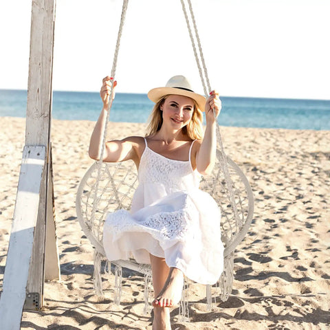 Woman sitting in a Cozy Hammock Chair Set Of 2 Macrame Swing Chairs With Tassels Bohemian Style Handwoven Cotton Rope Indoor Outdoor Beige