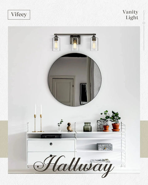 Three Light Vanity Lights With Dope Oil Rubbed Bronze Finish And Clear Glass Shades above a hallway mirror and shelf with decor