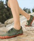 Close-up of green water shoes on feet walking on rocks, showcasing Water Shoes For Men And Women Aqua Swim Shoes Quick Dry Barefoot Footwear.