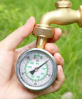 Person holding a 2 Inch Glycerin Filled Stainless Steel Water Pressure Gauge Built For Home And Garden Use, connected to a hose.