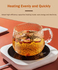Smart Desk Electric Coffee Mug Warmer With Three Adjustable Heat Settings And Twelve Hour Auto Shut Off keeping tea warm in a glass mug.