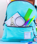 Quarter Inch Handheld Hole Punch For DIY Crafts And School Projects in a backpack with pens and a ruler.