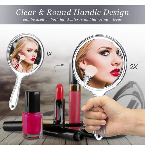 Double Sided Handheld Mirror With 1X And 2X Magnification Clear Handle Round Makeup Mirror For Face Detailing And Mascara Application Great For On The Go showing 1x and 2x magnification with cosmetics in the background.