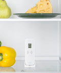 Front view of white La Crosse Technology wireless refrigerator/freezer thermometer with magnetic back on a fridge shelf.